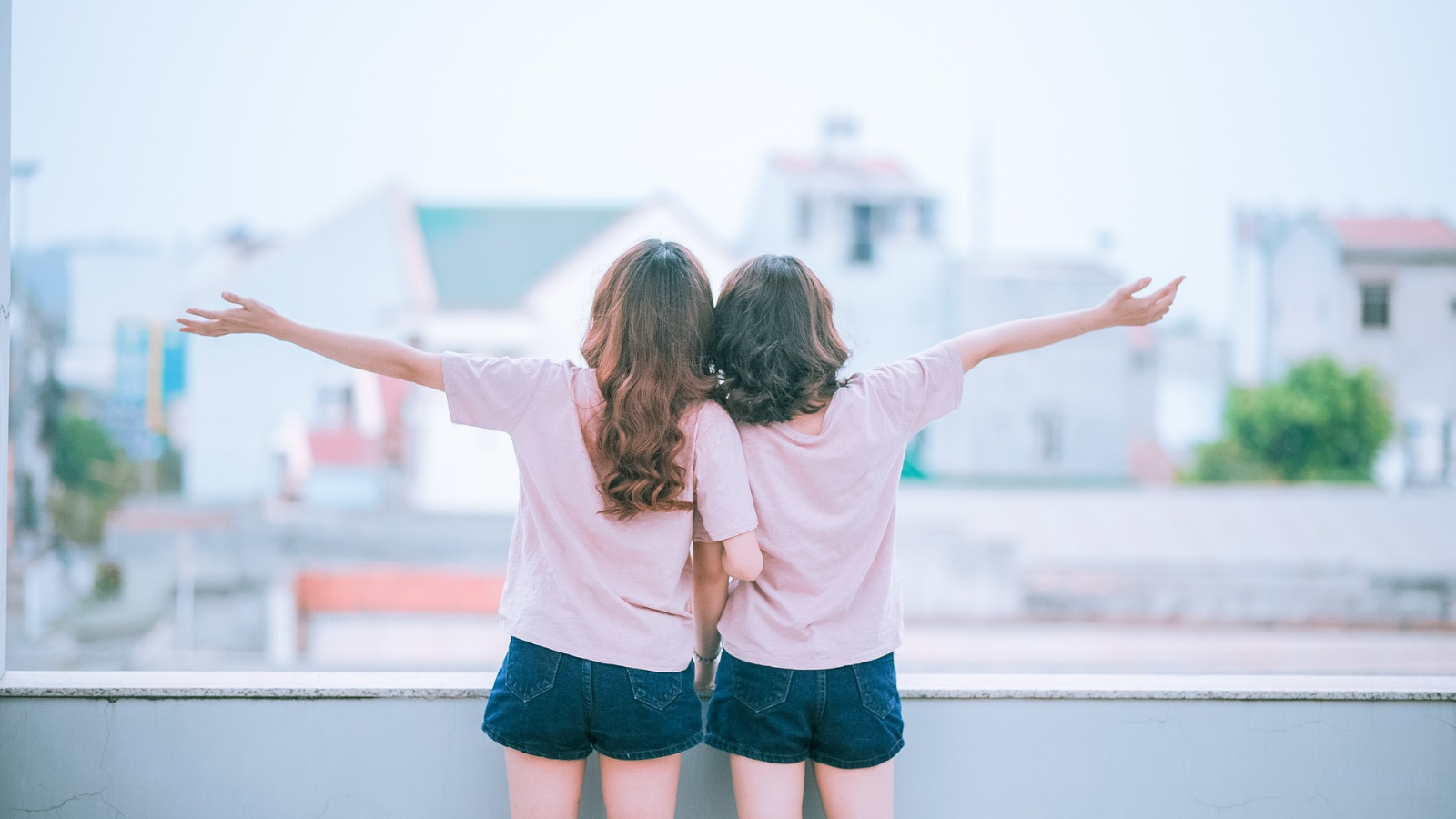 Zwei junge Frauen genießen die Aussicht vom Balkon.