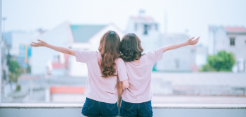 Zwei junge Frauen genießen die Aussicht vom Balkon.