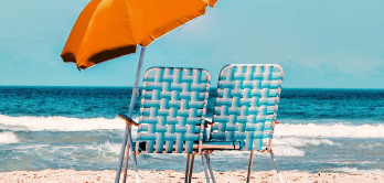Sonnenschirm orange mit zwei Stühlen am Strand